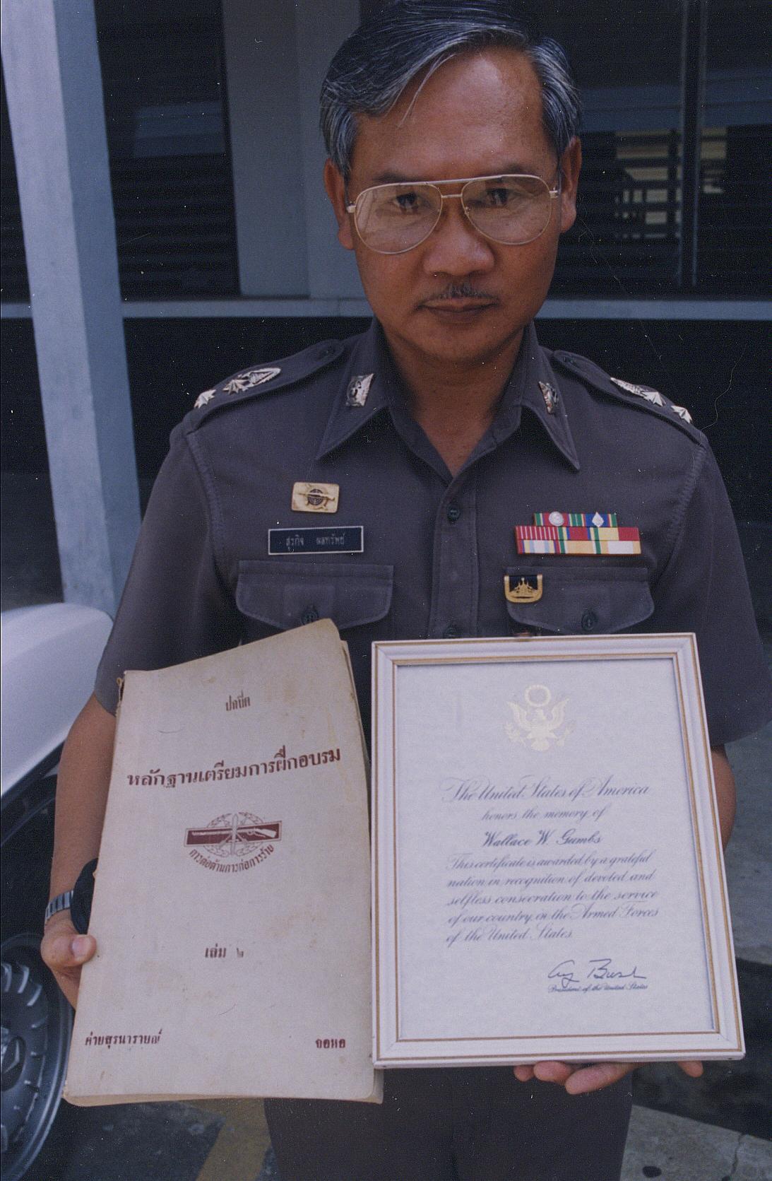 Royal Thai Police Commander, Lt Colonel, holding a copy of our book, Counterinsurgency Training for Police Officers, and a copy of a letter from President George Bush I, regarding the death of SSG Wallace Gumbs