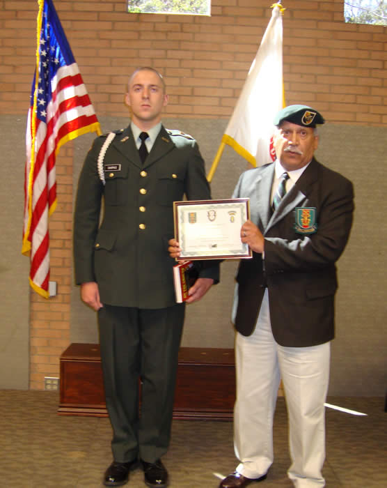 Terry Cagnolatti presenting Special Forces Certificate and Medal of Merit and a copy of  'Tilt'  Striker Meyers book, "On the Ground" to  USC Cadet David Shipko.