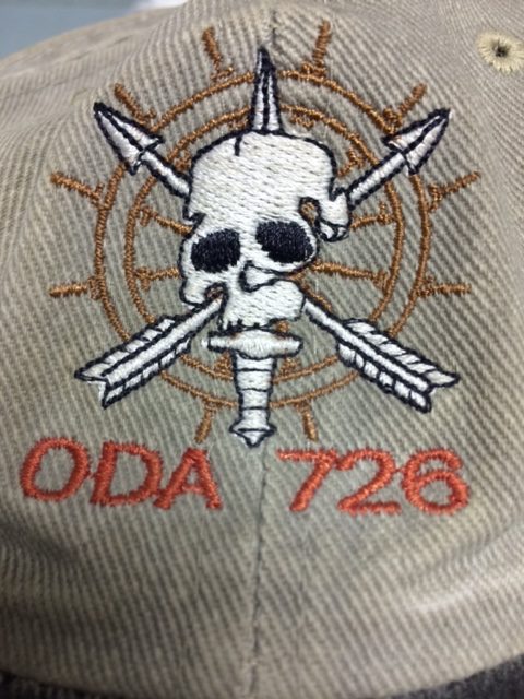 The ODA 726 logo stitched on Joff’s baseball cap from downrange, which he’d given to Alex. He’d written the names of fallen SF brothers on the inside of the cap.