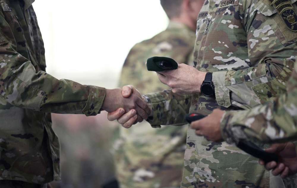 The commanding general of the U.S. Army John F. Kennedy Special Warfare Center and School, presents a green beret to a SFQC graduate (U.S. Army photo by K. Kassens)