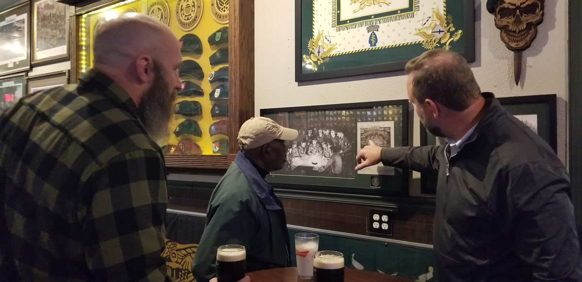 Left to right, Mike Jackson, Lew Chapman, and a patron pointing out a picture he is enthusiastic about. (How Miller)